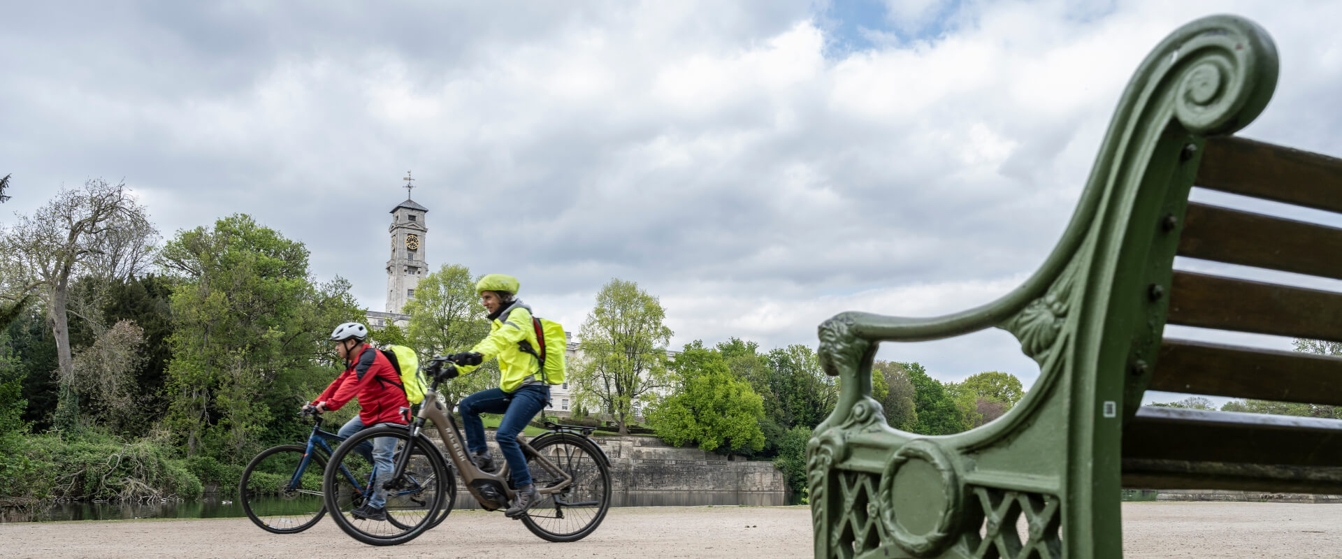 Two people cycling along a path in a park.