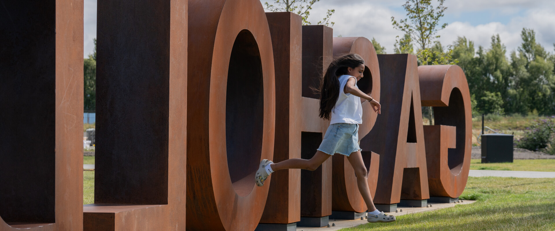A young girl jumping from a a structure of letters.